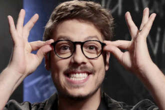 Fábio Porchat sorrindo com a mão nos óculos