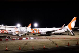 Aeronave da GOL estacionada no pátio do Aeroporto Internacional Tom Jobim (Galeão), à noite, conectada à ponte de embarque e iluminada pelos refletores do terminal, durante a inauguração da rota direta entre Rio de Janeiro e Nova York.