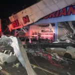 Estrutura de estabelecimento destruída e veículos atingidos após a passagem do ciclone bomba no Rio Grande do Sul.