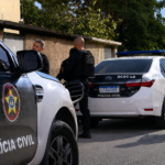 Agentes da Polícia Civil ao lado de duas viaturas durante a Operação Golpe de Fé.