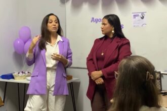 Pessoa segura dois folhetos roxos, um do Agosto Lilás, com o ciclo da violência contra a mulher, e outro com a frase “Não é não! Respeite a decisão”.