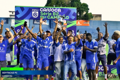 Jogadores e integrantes do Goytacaz comemoram o título da Série B2 do Campeonato Carioca com o troféu erguido.