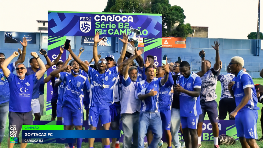 Jogadores e integrantes do Goytacaz comemoram o título da Série B2 do Campeonato Carioca com o troféu erguido.
