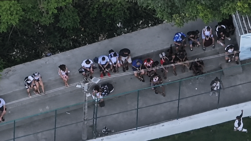 Imagem aérea mostra grupo de pessoas reunido ao lado de uma quadra no Complexo da Penha.