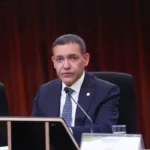 Presidente do TSE, ministro Kassio Nunes Marques, sentado diante de um microfone durante cerimônia do tribunal.