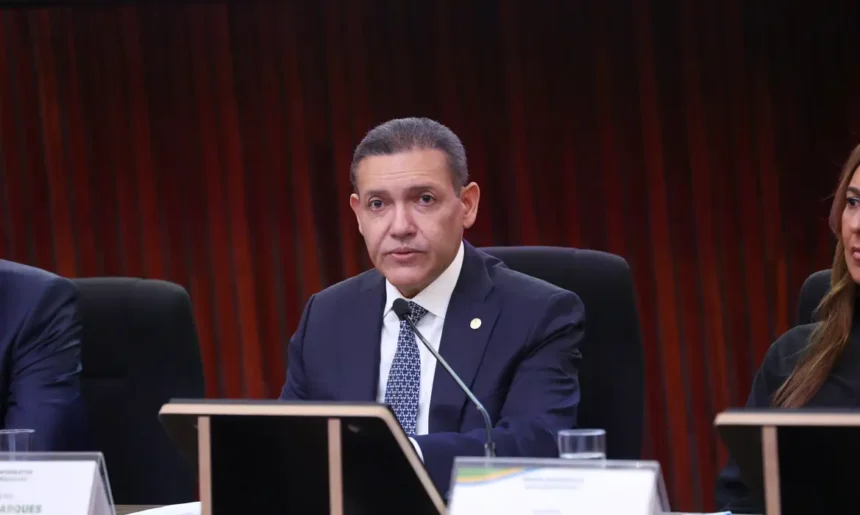 Presidente do TSE, ministro Kassio Nunes Marques, sentado diante de um microfone durante cerimônia do tribunal.