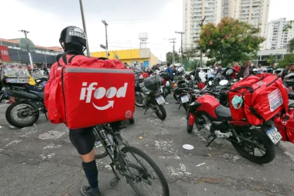 Entregador do iFood com bicicleta em meio a motocicletas e outros trabalhadores de aplicativos.