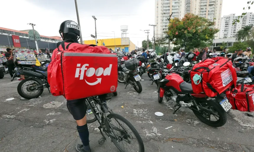 Entregador do iFood com bicicleta em meio a motocicletas e outros trabalhadores de aplicativos.