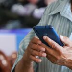 Homem segura e utiliza um telefone celular em um local público.