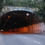Entrada do Túnel Raul Veiga, em Niterói, com dois carros circulando pela via cercada por vegetação.