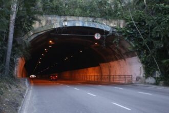 Entrada do Túnel Raul Veiga, em Niterói, com dois carros circulando pela via cercada por vegetação.