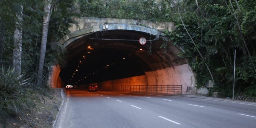 Entrada do Túnel Raul Veiga, em Niterói, com dois carros circulando pela via cercada por vegetação.