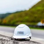 Capacete branco com a marca da Arteris Fluminense sobre uma barreira de concreto às margens da BR-101.