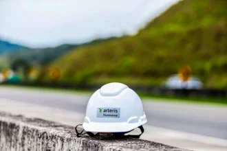 Capacete branco com a marca da Arteris Fluminense sobre uma barreira de concreto às margens da BR-101.