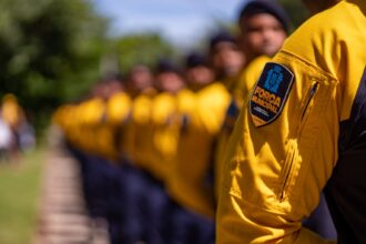 Agentes da Força Municipal do Rio em formação, com o emblema da corporação em destaque na manga do uniforme amarelo de um deles.