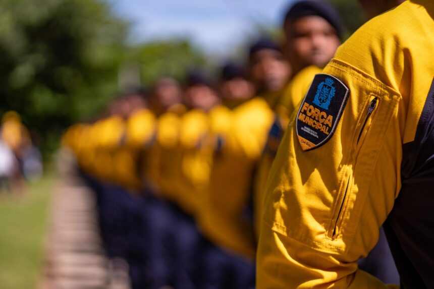 Agentes da Força Municipal do Rio em formação, com o emblema da corporação em destaque na manga do uniforme amarelo de um deles.